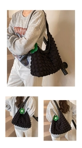 Detail of black bubble textured tote bag featuring a vibrant green flower charm
