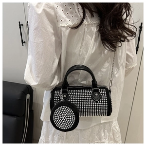 Détail du sac cylindrique noir clouté avec pochette ronde porté sur l'épaule pour femme