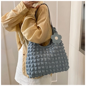 Close-up of light blue bubble textured tote bag with a grey floral charm detail
