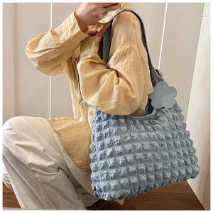 Close-up of light blue tote bag featuring 3D bubble texture and a floral charm pendant