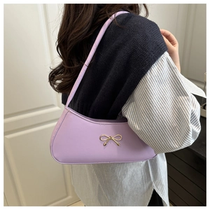Close-up of a lavender baguette bag featuring a golden bow accent on a model's shoulder