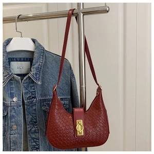 Detail shot of a dark red woven leather crescent bag with elegant gold metal buckle closure