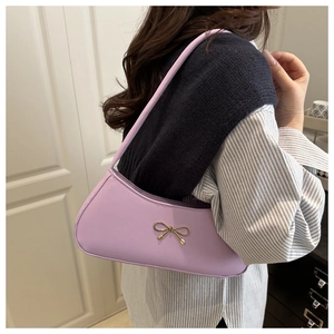 Macro detail of lavender underarm bag featuring a delicate golden bow metal buckle