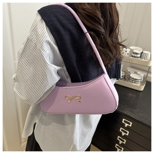 Detail of light purple underarm bag with gold bow buckle and smooth leather texture