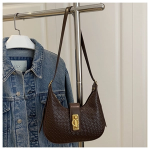 Detail of dark brown woven texture handbag with golden round buckle on a hanger