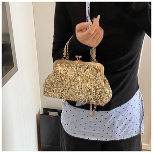 Detail of elegant gold sequin evening clutch featuring ornate metal handle and frame