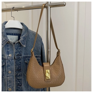 Detail of camel woven texture crescent bag with golden round metal buckle on shoulder strap