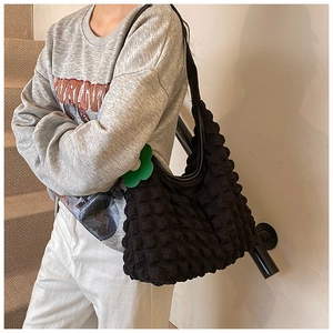 Detail of black popcorn texture shoulder bag with green flower charm on stairs