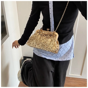 Close-up of golden sequins evening bag with round metallic clasp and chain strap