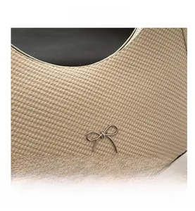Detail of beige woven fabric texture and silver metal bow buckle on crescent shoulder bag