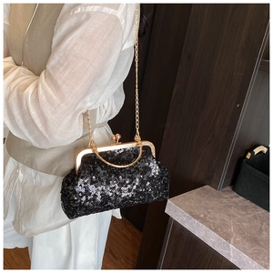 Detail of black sequin crossbody bag with gold chain and circular handle shown on model