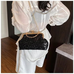 Detail view of black sequined shell bag with gold chain strap on white shirt model