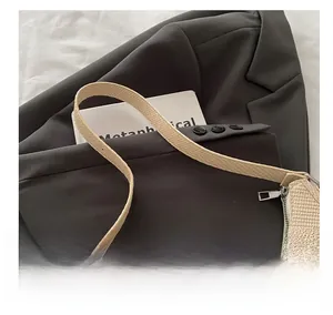 Close-up of the woven texture and silver zipper detail on a beige crescent shoulder bag