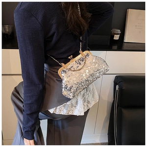 Detail of silver sequin shell bag featuring a gold metal clasp and slender chain strap