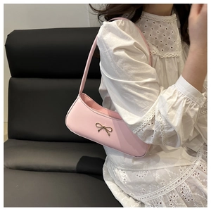 Close-up of pink underarm bag with gold bow buckle worn by model in lace dress