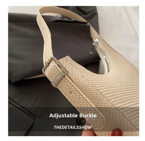 Detailed macro view of the silver adjustable metal buckle on a beige woven crescent bag