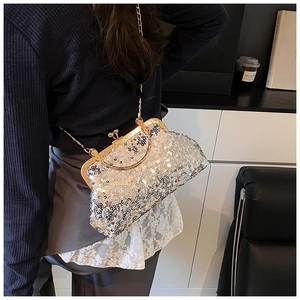 Detail of silver sequin evening bag with gold chain strap on a vintage leather sofa