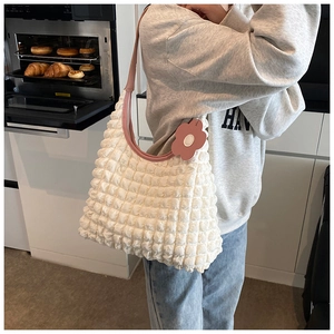 Detail of white bubble texture tote bag with pink leather strap and floral charm accessory