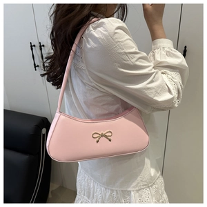 Detail of pink leather underarm bag with a golden metal bow and elegant lace shirt