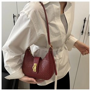Detail of burgundy crescent hobo bag featuring woven texture and gold metal buckle