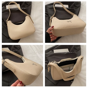 Detail showing beige woven crescent bag texture with silver bow charm and interior space