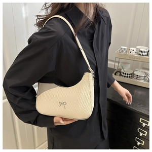 Model wearing a minimalist cream crescent hobo bag with a silver bow accent
