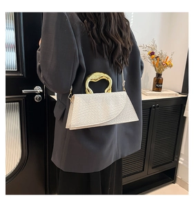 Détail du sac à main en cuir tressé blanc avec poignée anneau dorée et bandoulière