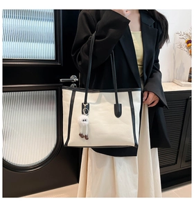 Lifestyle shot of large cream and black tote bag with cute plush pendant accessory