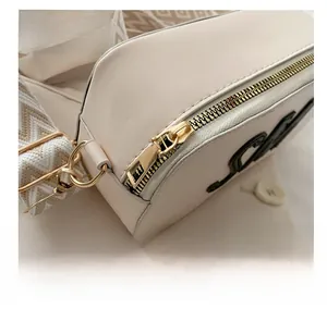 Detail des glatten Goldreißverschlusses und der strukturierten beigen Leder-Umhängetasche