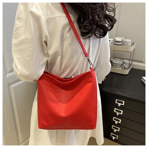 Macro detail of the bright red minimalist leather tote bag with a slim shoulder strap