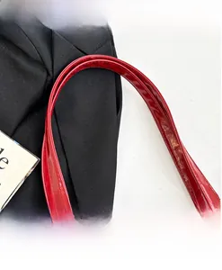 Close-up of red patent leather shoulder strap with fine stitching on a tote bag