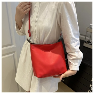 Detailed view of the vibrant red PU leather tote bag worn with a white dress