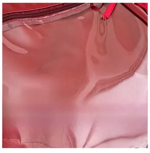 Detail display of the shiny red leather tote bag with smooth zipper and premium stitching