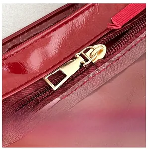 Close-up of polished gold metal zipper on luxury red patent leather handbag