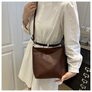 Model wearing dark brown vintage bucket bag with adjustable shoulder strap in modern setting