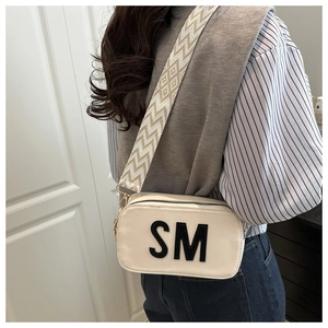 Detail der cremefarbenen Umhängetasche mit SM-Logo und geometrischem breitem Schultergurt