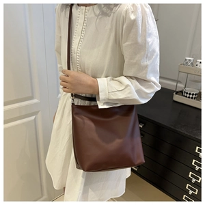 Brown faux leather tote bag worn over the shoulder with minimalist chic design