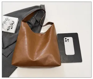 Flat lay of brown hobo tote bag with wide strap and detailed leather texture