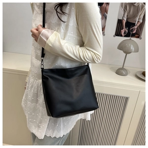 Detail of minimalist black matte leather tote bag with slim shoulder strap and metal hooks