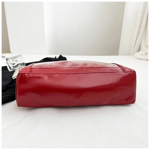 Detail of red glossy tote bag with transparent PVC window and smooth leather texture