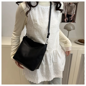 Detail view of black PU leather bucket bag with adjustable strap and silver metal buckles