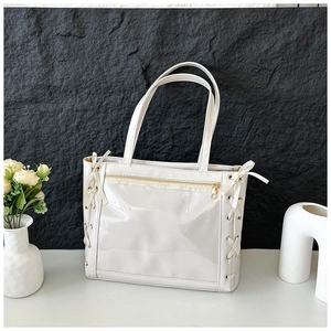 Detail of white tote bag featuring transparent PVC window and elegant ribbon bows