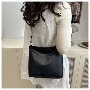 Minimalist black tote bag shown on model in a cozy interior setting for daily commute
