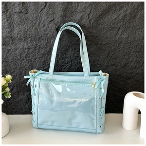Detail of light blue ita bag with transparent window, ribbon bows and patent leather finish