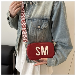 Details der roten quadratischen Canvas-Tasche mit weißen SM-Buchstaben und Gurt
