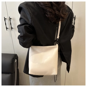 Sac fourre-tout crème minimaliste porté à l'épaule sur un mannequin en intérieur