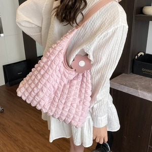 Pink popcorn texture shoulder bag with wide strap and floral charm accessory for women