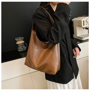 Detail of caramel brown leather tote featuring soft pebble texture and wide shoulder strap