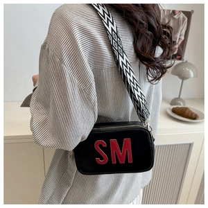 Detail of black crossbody bag with red SM letter embroidery and geometric strap