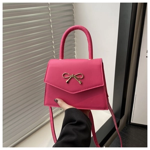 Detail of a pink mini handbag with a golden bow buckle and smooth PU leather finish